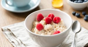 Healthy Breakfast Oatmeal Porridge Bowl With Berries Honey. Cup of green tea on background. Nutrition, healthy eating, healthy breakfast concept