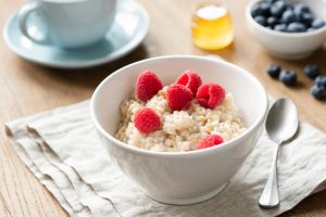 Healthy Breakfast Oatmeal Porridge Bowl With Berries Honey. Cup of green tea on background. Nutrition, healthy eating, healthy breakfast concept